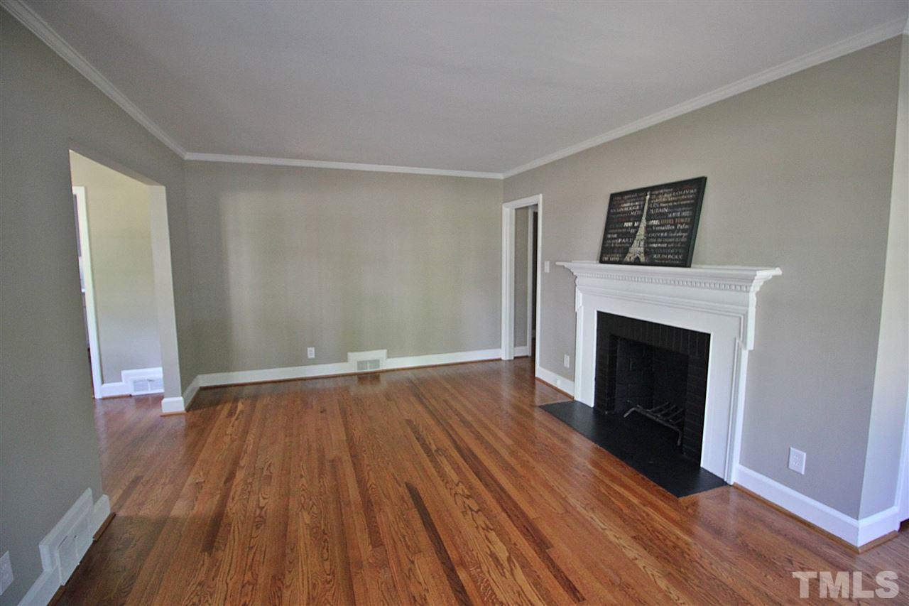 1204 Mitchell Street Raleigh, NC 27607 - Photo 2 of 22 a view of an empty room with wooden floor and a fireplace