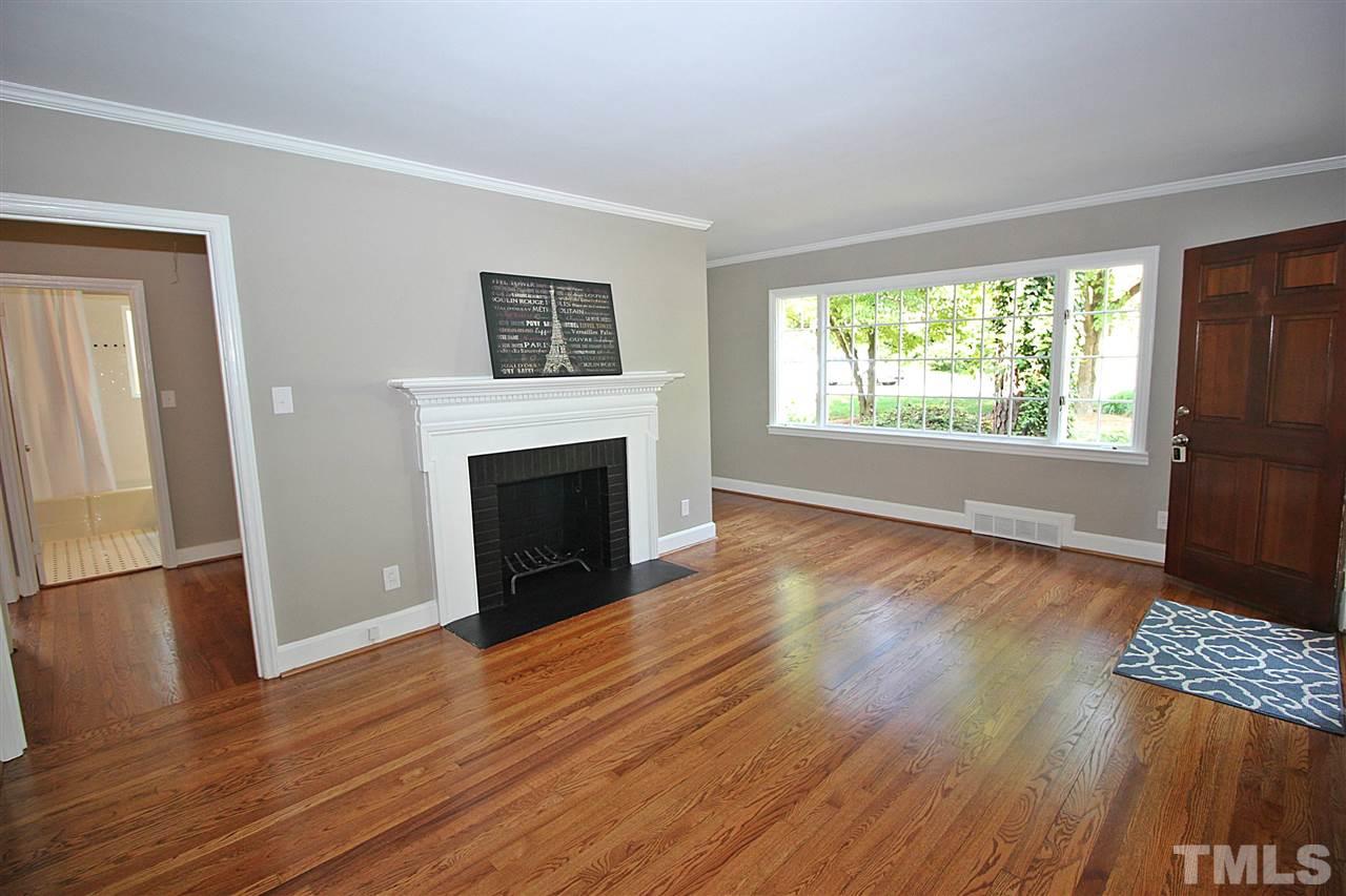 1204 Mitchell Street Raleigh, NC 27607 - Photo 5 of 22 an empty room with wooden floor fireplace and windows