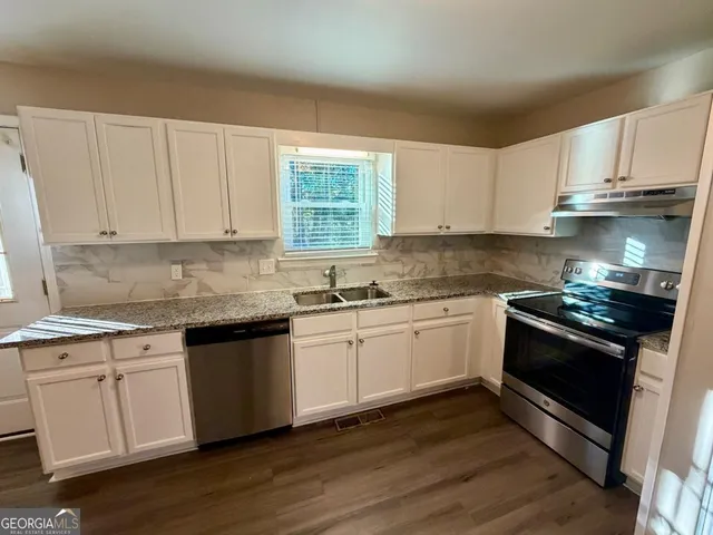 a kitchen with granite countertop wooden cabinets and a stove