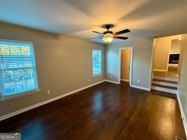 a view of an empty room with window and wooden floor
