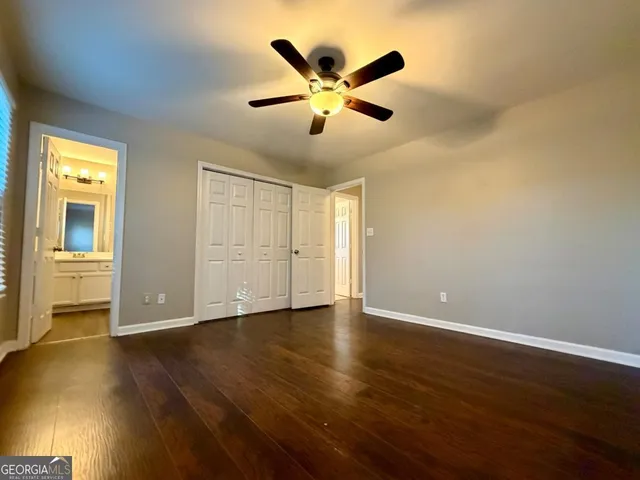 a view of an empty room with wooden floor and a ceiling fan