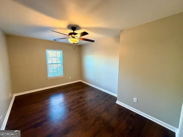 an empty room with wooden floor fan and windows