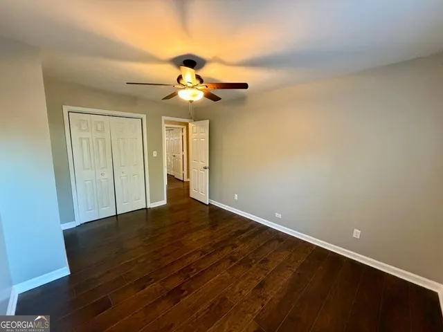 a view of a room with a ceiling fan and wooden floor