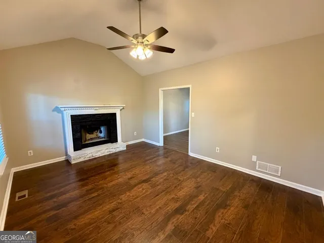 an empty room with wooden floor a fireplace and chandelier fan