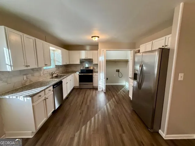 a kitchen with stainless steel appliances a refrigerator sink and wooden floor