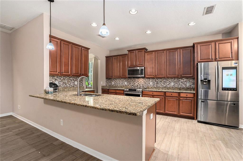 10737 Breaking Rocks Drive Tampa, FL 33647 - Photo 9 of 28 a kitchen with stainless steel appliances granite countertop a sink refrigerator and microwave