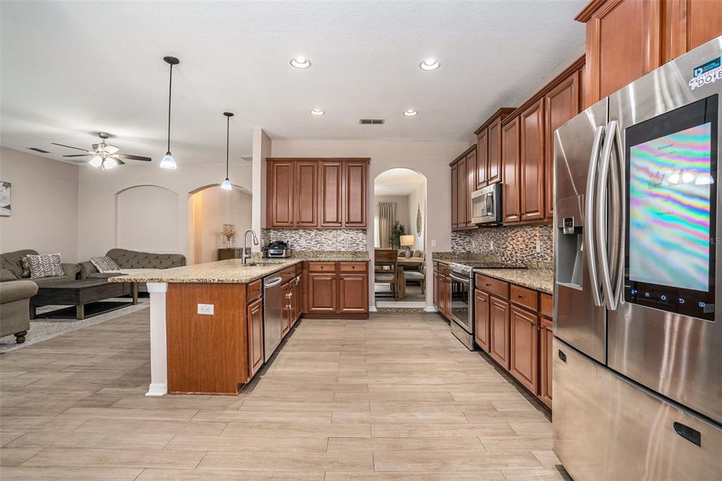 10737 Breaking Rocks Drive Tampa, FL 33647 - Photo 10 of 28 a large kitchen with stainless steel appliances kitchen island granite countertop a large counter top a stove a sink and a refrigerator