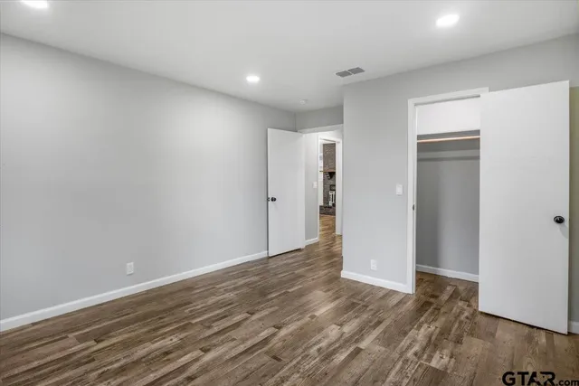 a view of an empty room with wooden floor and closet