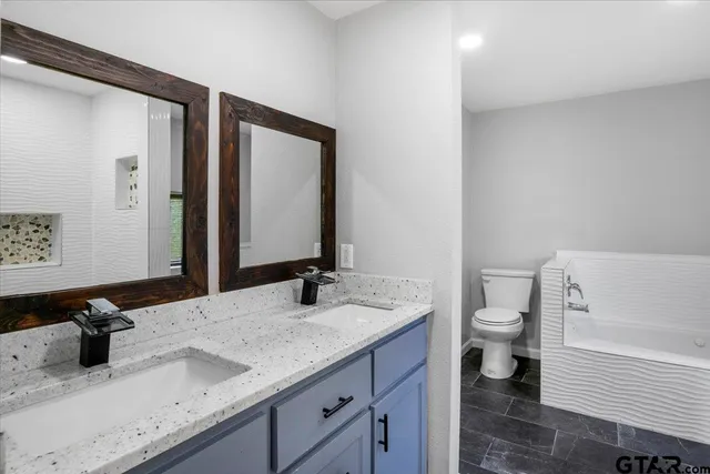 a bathroom with a granite countertop sink toilet and mirror