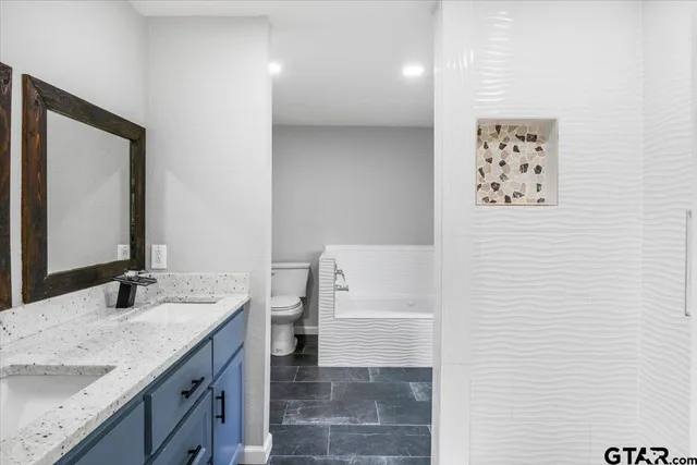 a bathroom with a granite countertop sink a toilet and a mirror