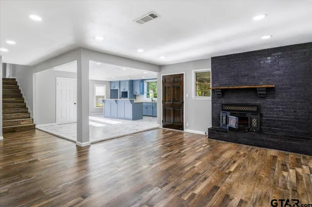 an empty room with wooden floor and a kitchen