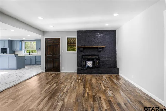 a view of empty room with kitchen and fireplace
