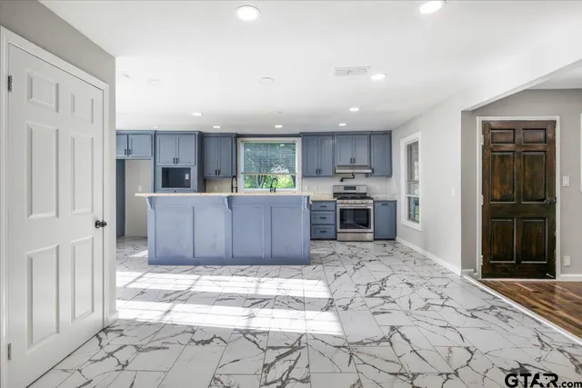 a large kitchen with kitchen island granite countertop a refrigerator and a sink