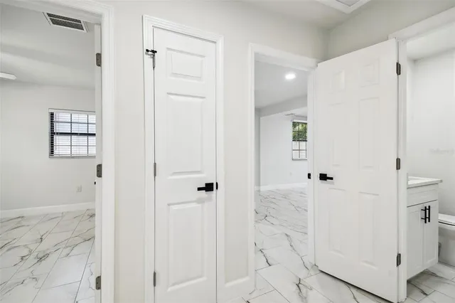 an empty room with a chandelier fan and windows