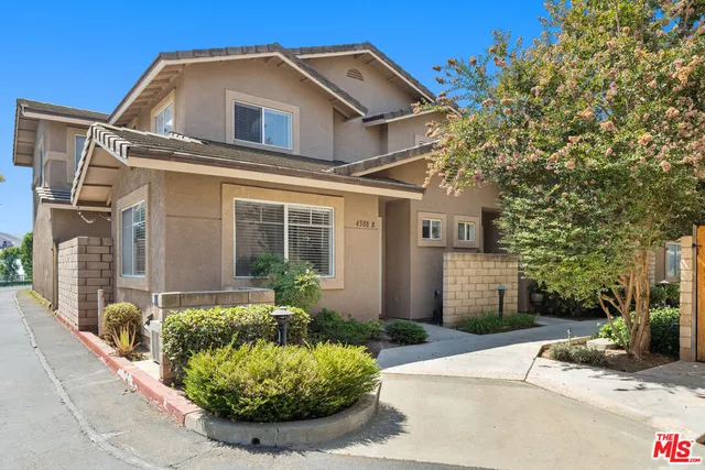 a view of a white house with a small yard and potted plants