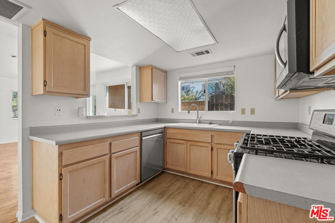 4508 Apricot Road, Unit B Simi Valley, CA 93063 - Photo 7 of 17 a kitchen with stainless steel appliances granite countertop a stove a sink dishwasher and white cabinets with wooden floor