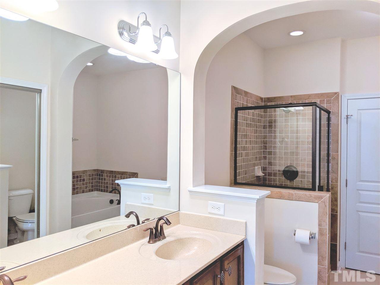 9244 Wooden Road Raleigh, NC 27617 - Photo 9 of 11 Owner's Bath features tall vanity w/dual sinks & archway leading to garden tub and separate shower detailed with ceramic tile.