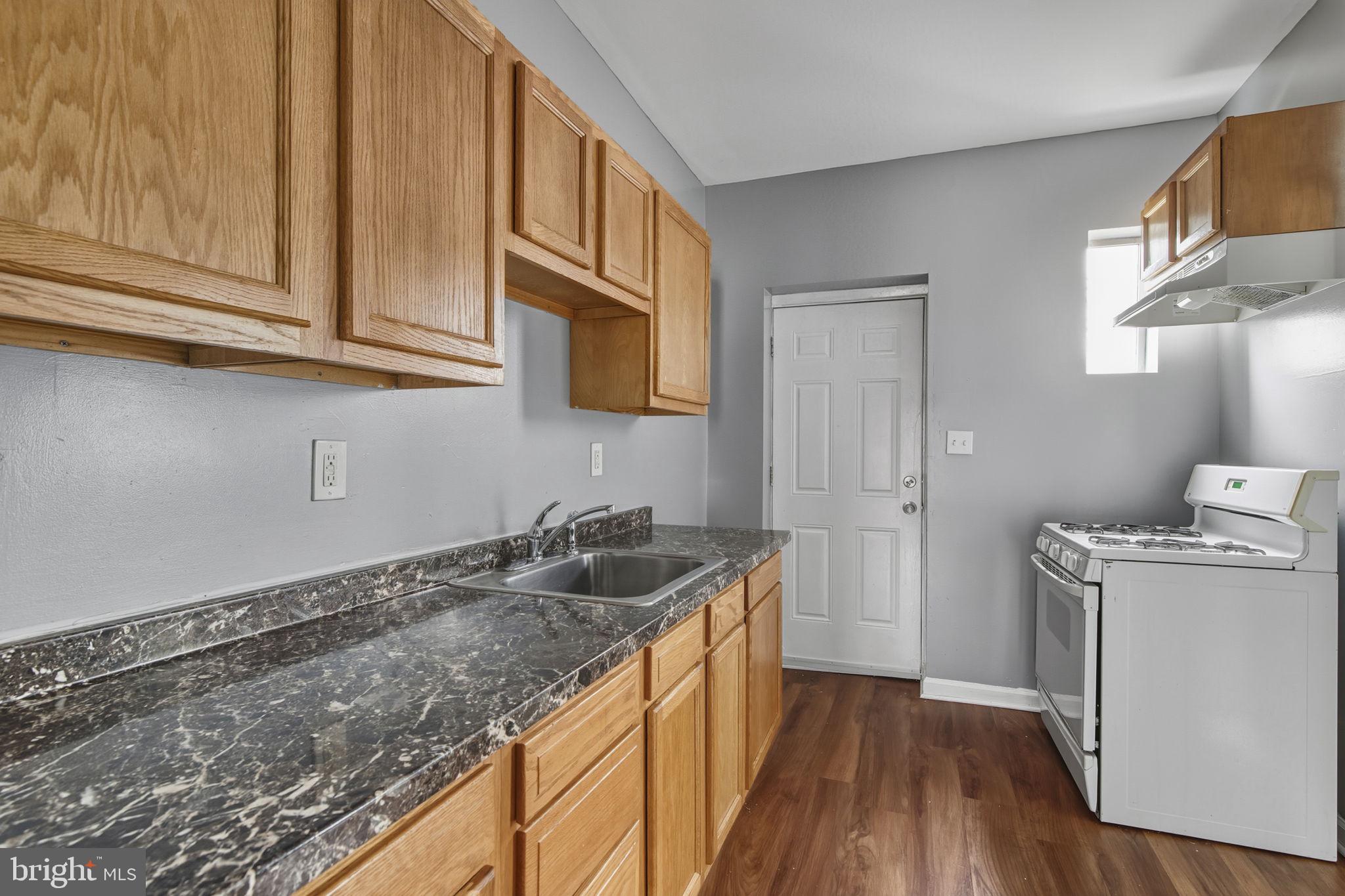 1209 North Dukeland Street Baltimore, MD 21216 - Photo 5 of 21 a kitchen with a sink stove and cabinets