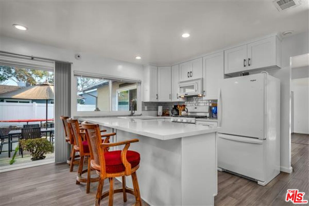 5118 Randall Street Los Angeles, CA 90230 - Photo 12 of 26 a kitchen with stainless steel appliances granite countertop a refrigerator a stove a sink dishwasher and a dining table with wooden floor