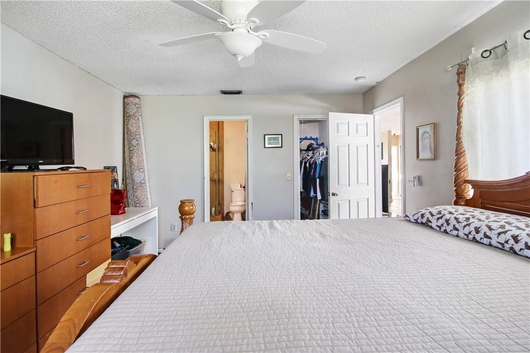 9157 Southwest 5th Street, Unit B Boca Raton, FL 33428 - Photo 11 of 21 a bedroom with a bed and a flat tv screen on dresser