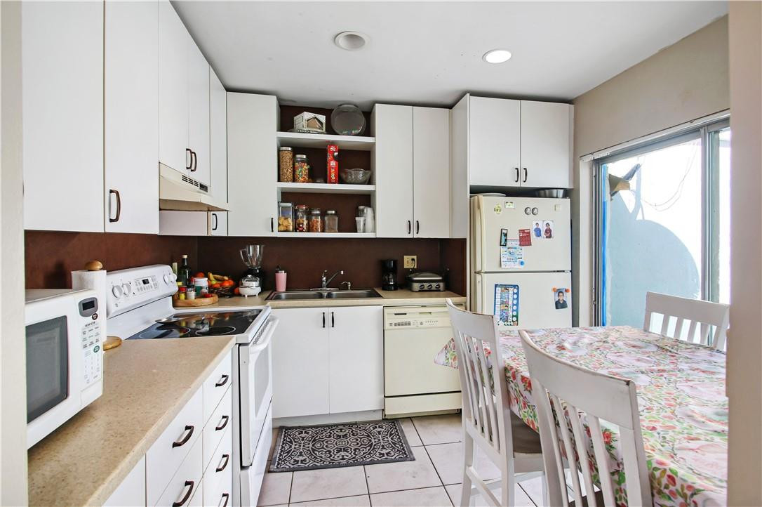 9157 Southwest 5th Street, Unit B Boca Raton, FL 33428 - Photo 7 of 21 a kitchen with a sink a stove and white cabinets