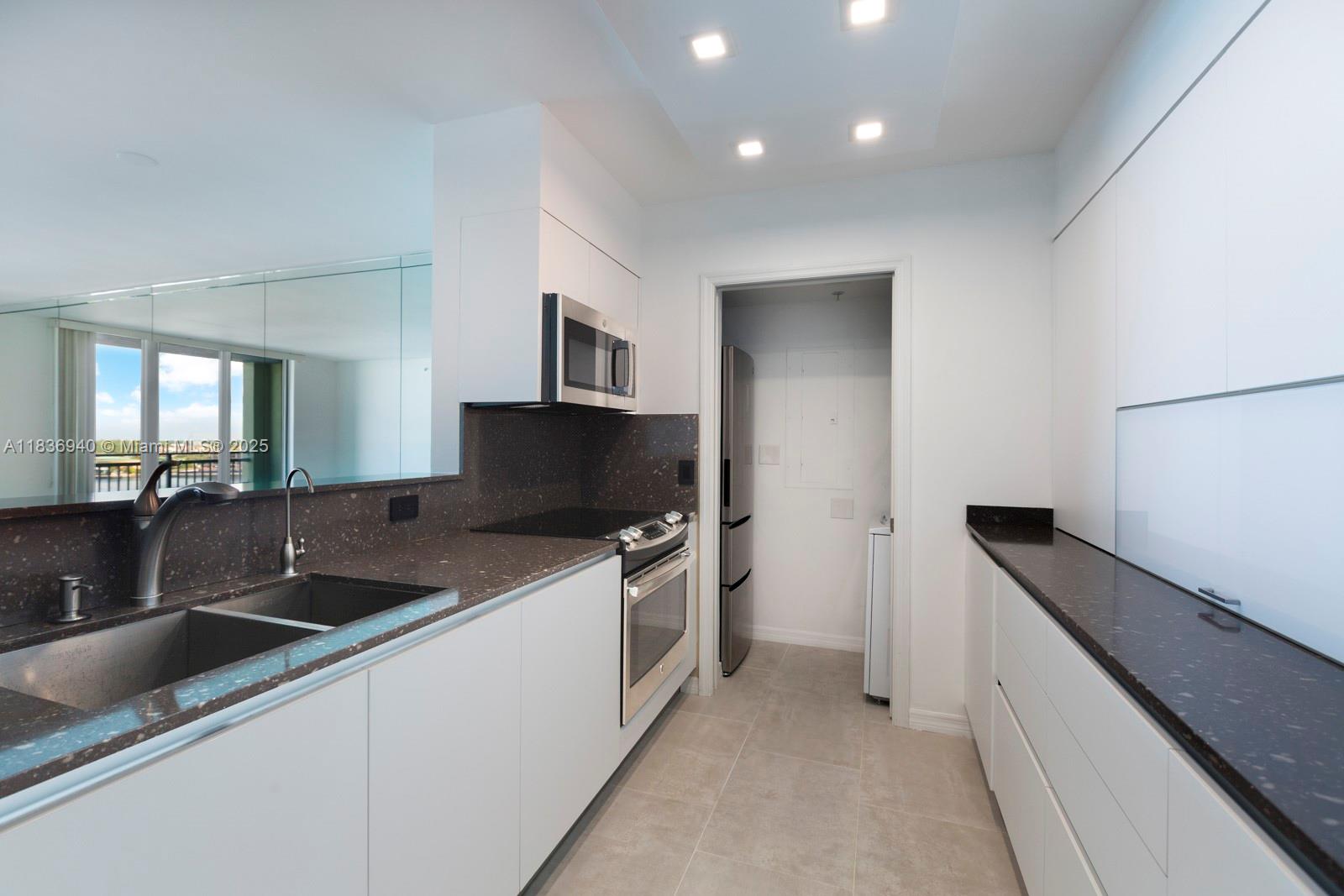 90 Alton Road, Unit 1408 Miami Beach, FL 33139 - Photo 9 of 15 a kitchen with granite countertop a sink and a stove top oven