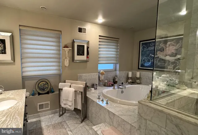 a bathroom with a tub shower sink and mirror