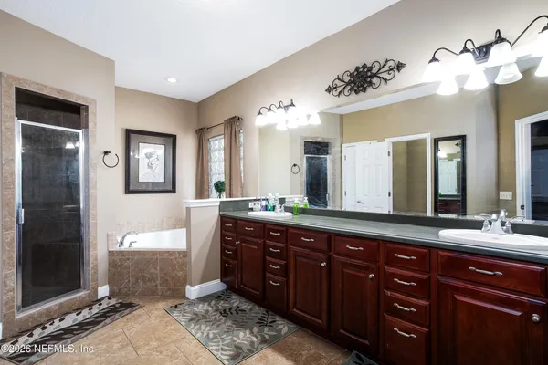 a spacious bathroom with a granite countertop double vanity sink a mirror and a shower