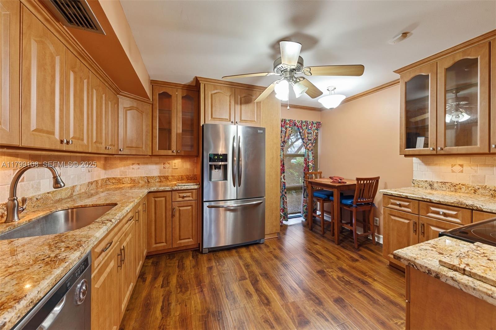 6668 Burning Wood Drive, Unit 166 Boca Raton, FL 33433 - Photo 13 of 27 a kitchen with stainless steel appliances granite countertop a refrigerator a stove top oven a sink dishwasher and wooden cabinets with wooden floor
