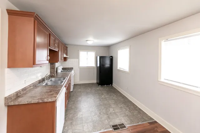 a kitchen with granite countertop a refrigerator stove oven sink and cabinets