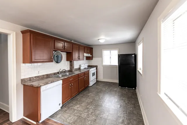 a large kitchen with stainless steel appliances granite countertop a stove a refrigerator a sink a oven and dishwasher with wooden floor