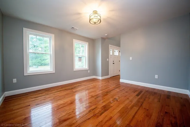 an empty room with wooden floor and windows