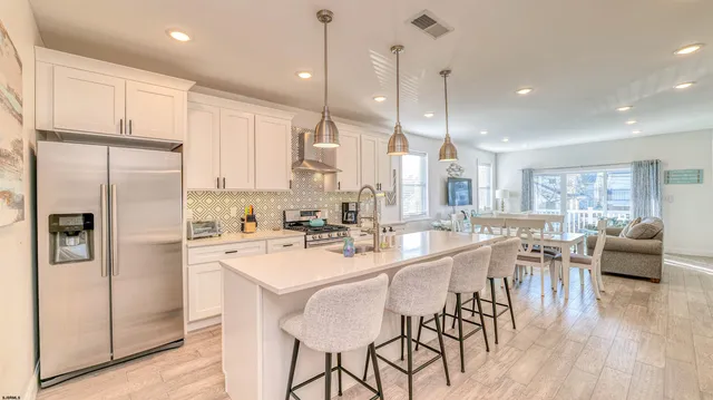 a kitchen with stainless steel appliances granite countertop a refrigerator a sink dishwasher a stove and white cabinets with wooden floor