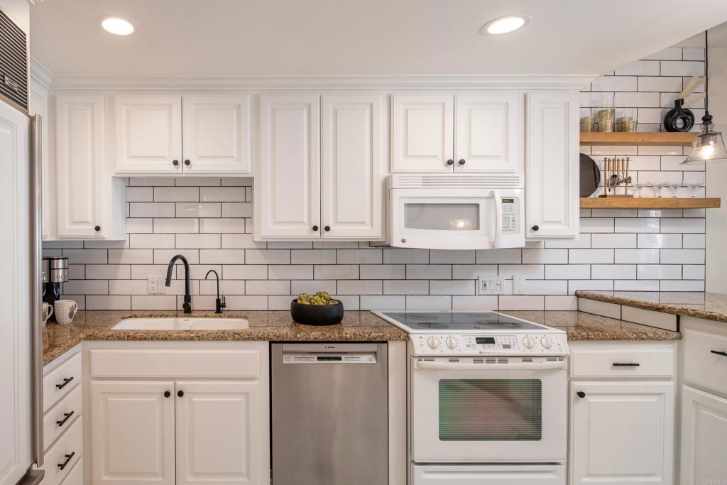 2005 Costa Del Mar Road, Unit 627 Carlsbad, CA 92009 - Photo 14 of 21 a kitchen with white cabinets and white appliances