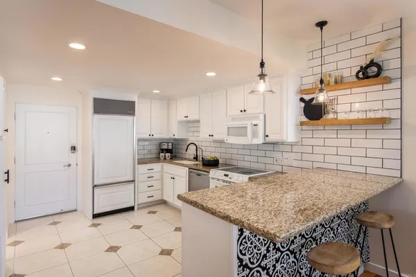 a kitchen with a sink a stove a refrigerator and white cabinets