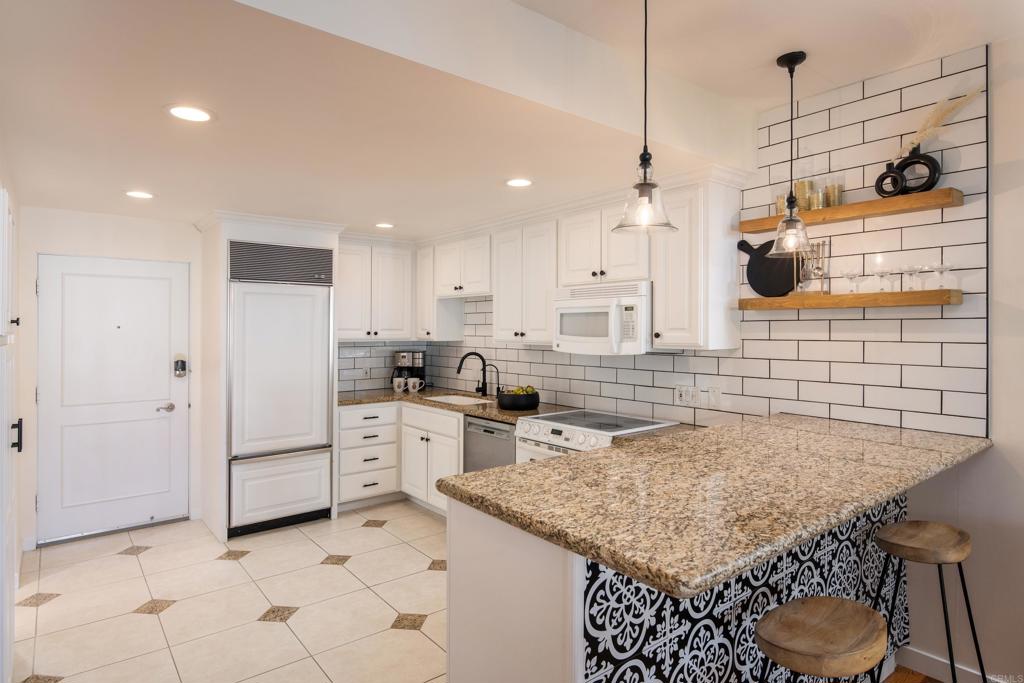 2005 Costa Del Mar Road, Unit 627 Carlsbad, CA 92009 - Photo 15 of 21 a kitchen with a sink a stove a refrigerator and white cabinets