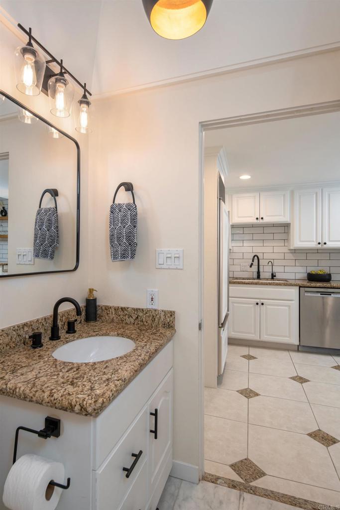 2005 Costa Del Mar Road, Unit 627 Carlsbad, CA 92009 - Photo 17 of 21 a bathroom with a granite countertop sink mirror and cabinets