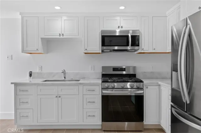 a kitchen with white cabinets and stainless steel appliances