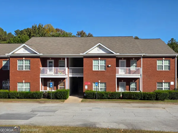a front view of a house with yard and parking