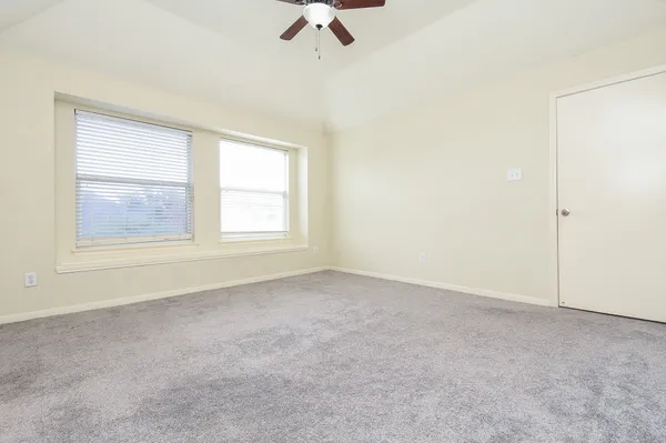an empty room with windows and fan