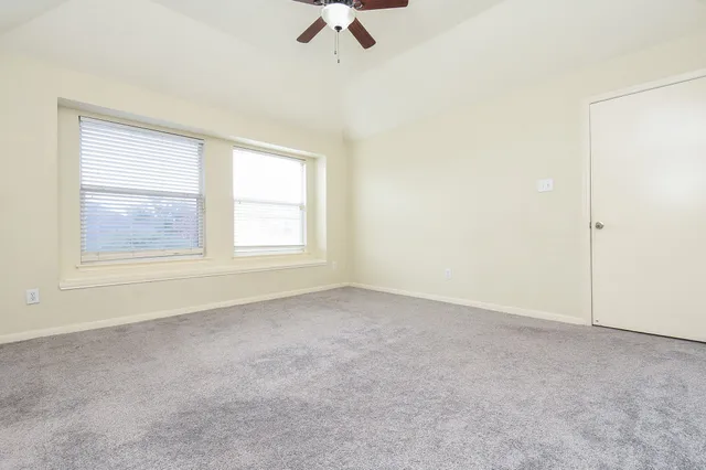 an empty room with windows and fan