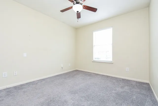 an empty room with a window and a fan