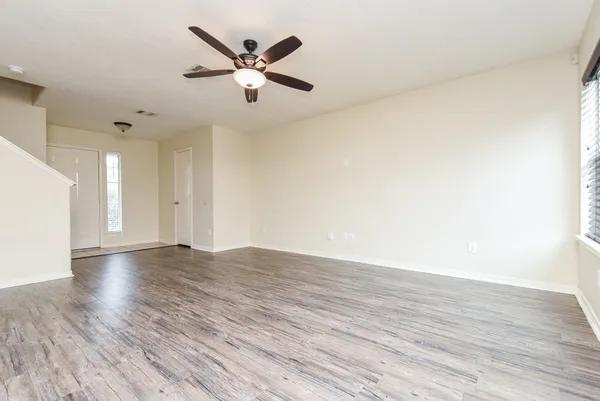 an empty room with wooden floor and a ceiling fan