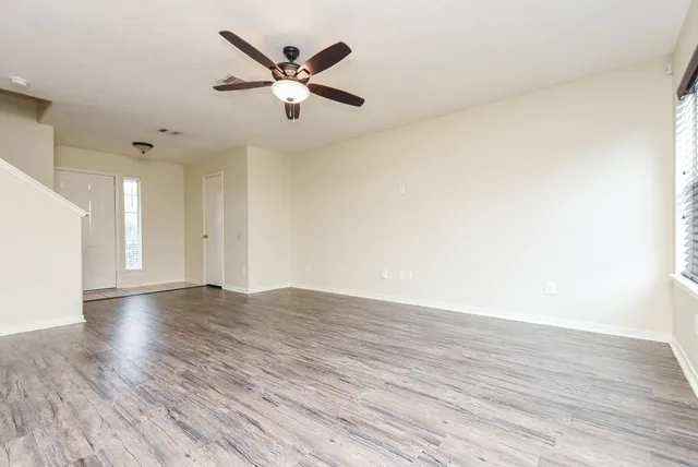 an empty room with wooden floor and a ceiling fan