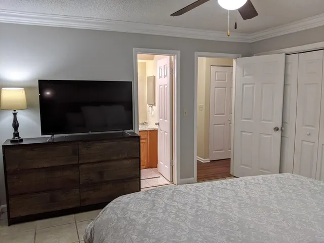 a bedroom with a bed and a flat tv screen on dresser
