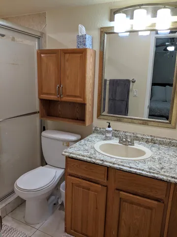 a bathroom with a granite countertop toilet sink and mirror