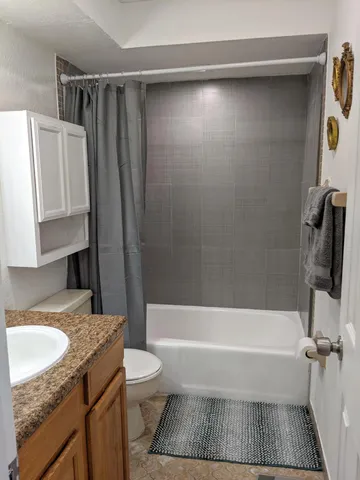 a bathroom with a granite countertop bathtub shower sink vanity and toilet