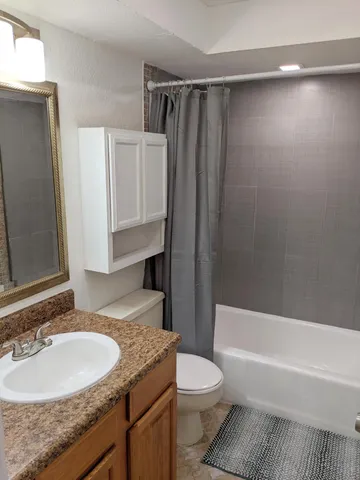 a bathroom with a granite countertop sink toilet and shower