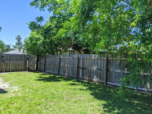 a view of a backyard with a fence and trees