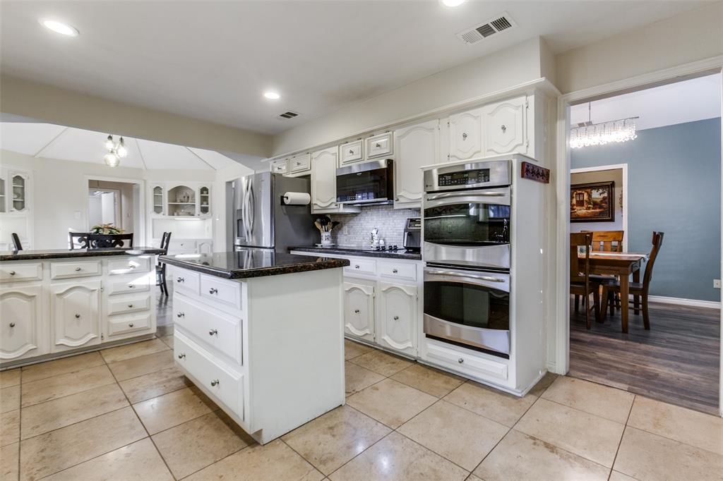 15881 Nedra Way Dallas, TX 75248 - Photo 4 of 26 a kitchen with stainless steel appliances granite countertop a stove top oven a sink and cabinets